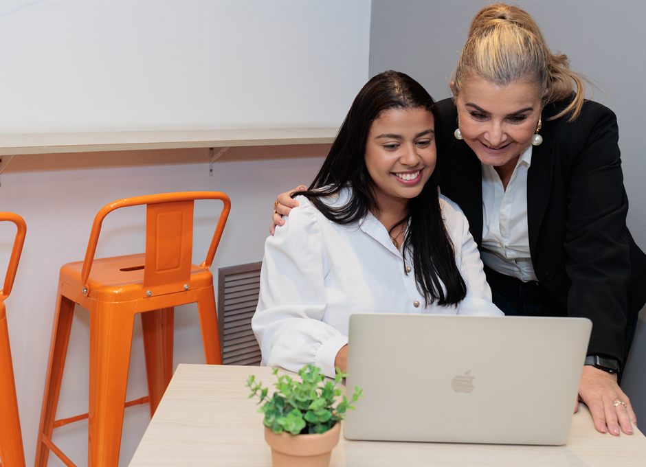 Duas colegas de trabalho vendo o resultado de um nivelamento no laptop