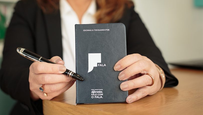 Documento sendo revisado à mão, com caderno e caneta sobre a mesa